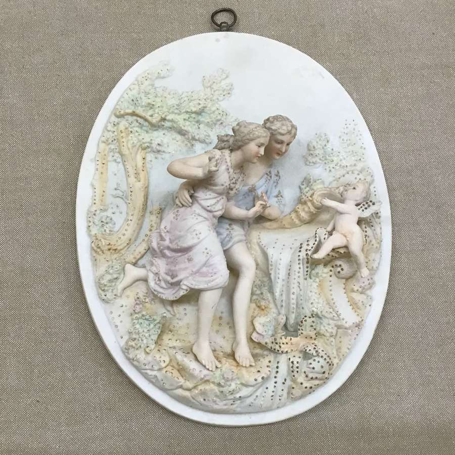 A bisque wall plaque with courting couple and cherub circa 1900