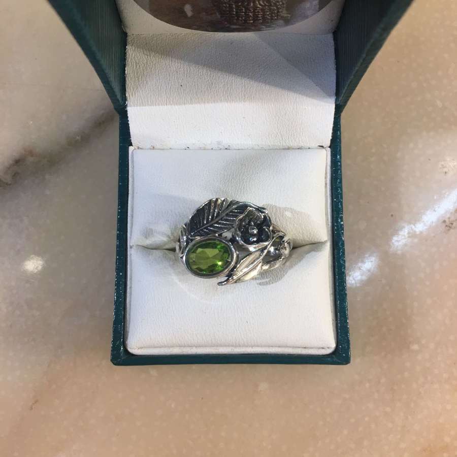 A sterling silver ring with a fected peridot flower and leaf design